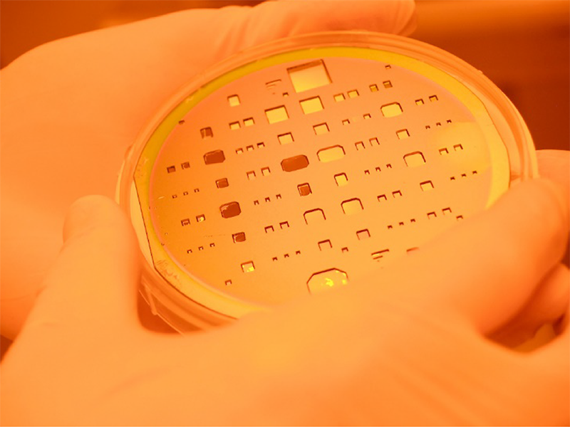 Photo of a lab worker holding microfabrication equipment